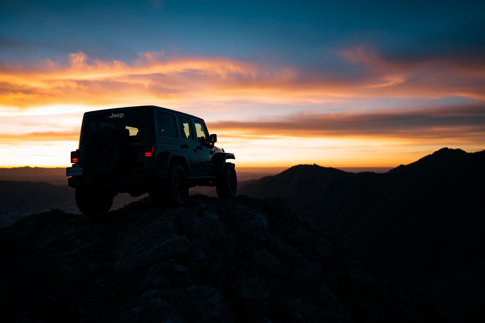 Modified Jeep on a mountain ridge at dusk